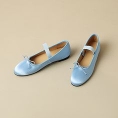 two pairs of blue shoes on a beige surface with one shoe tied up and the other closed