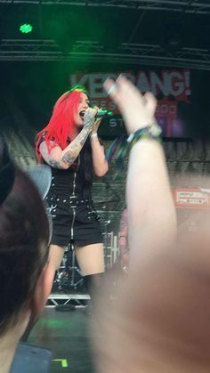 a woman with red hair singing on stage