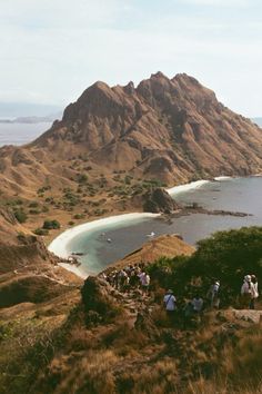 a group of people standing on top of a hill next to a body of water