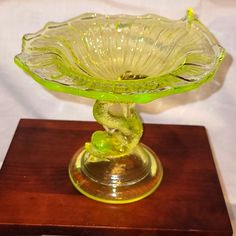 a yellow glass bowl sitting on top of a wooden stand