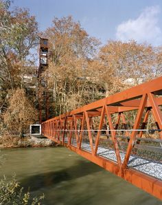 an orange bridge over water with trees in the background