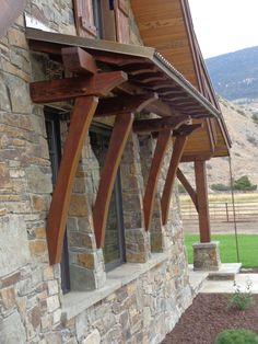 an outside view of a house with stone and wood columns on the side of it