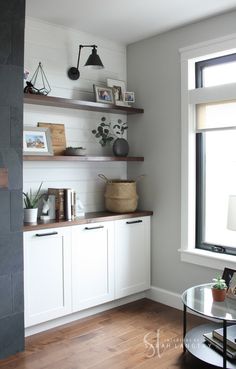 a living room filled with furniture next to a window covered in bookshelves and shelves