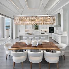 a dining room table with white chairs and a chandelier hanging from the ceiling