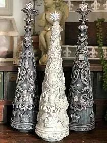 three silver and white christmas trees sitting on top of a wooden table next to a statue