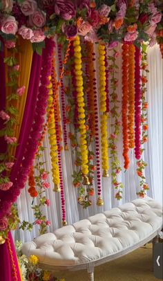 a white bench covered in lots of flowers and garlands next to a row of candles