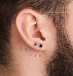 a man's ear is shown with three small black squares on the back of it