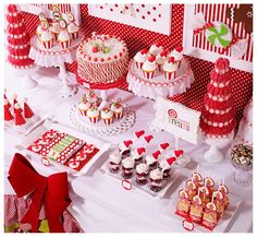 a table topped with lots of cakes and cupcakes on top of plates next to candy bars