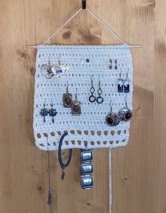 a white crocheted wall hanging with earrings and earring hooks attached to it