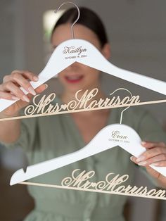 a woman holding three wooden hangers that say mr and mrs