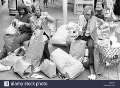 black and white photograph of women sitting on the ground with bags full of items in front of them