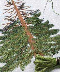 a close up of a piece of fabric with some thread on it and a pine tree in the background