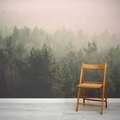 a wooden chair sitting in front of a forest wallpapered with foggy trees