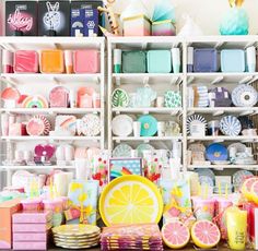 the shelves are filled with different types of plates, cups and napkins on them