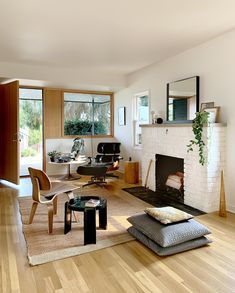 a living room filled with furniture and a fire place in the middle of a wooden floor