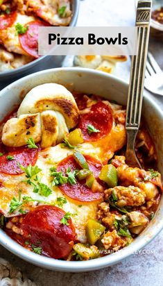 a bowl filled with pizza and meats next to a fork