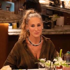 a woman sitting at a table with food and drinks