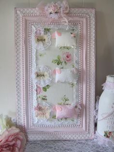 a pink frame with flowers on it sitting next to a bottle and some other items