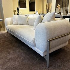 a white couch sitting on top of a carpeted floor next to a table and mirror