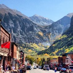 a street with cars parked on both sides and mountains in the background