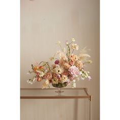 a vase filled with lots of flowers sitting on top of a wooden table next to a wall