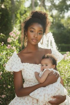 a woman in a white dress holding a small child with her arms around her chest