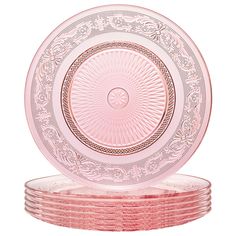 pink glass plates stacked on top of each other in front of a white background with an intricate design