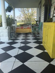 a black and white checkered floor with yellow furniture on the front porch next to it