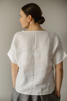 a woman standing in front of a white wall with her back turned to the camera