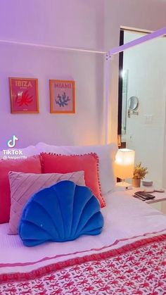 a bed with red and blue pillows on top of it next to a mirror in a room