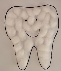 a tooth made out of cotton balls with a smile drawn on the front and side