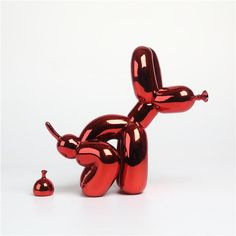 a red balloon dog sitting on top of a white floor next to a small object