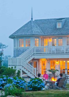 a large white house sitting on top of a lush green hillside next to a fire pit