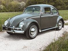 an old beetle is parked on a gravel road