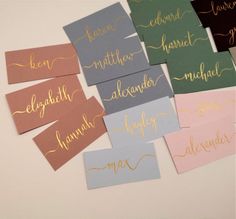 six handwritten name tags with gold foil on them, all in different colors and sizes