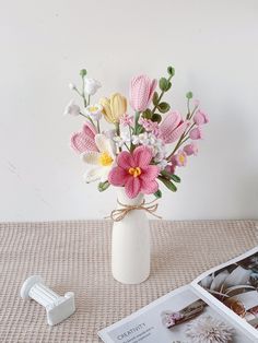 a vase filled with pink and white flowers on top of a table next to magazines