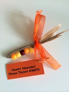 an orange tag with candy on it sitting next to a pair of carrots and a scissor