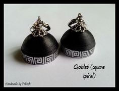 pair of black and white earrings with greek motif on each earring, both in silver