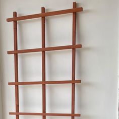 a wooden shelf with two vases sitting on top of it next to a white wall