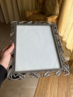 a person holding up a silver frame on the floor