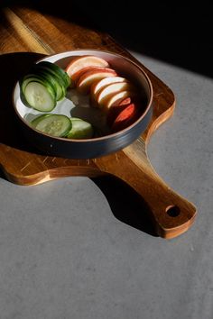 sliced cucumbers and apples in a pan on a cutting board