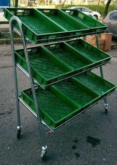 a green metal cart with four trays on it