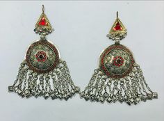 * This astonishing handpicked pair of tribal vintage earrings is a traditional ornament, stylish and classy both. * The unique ethnic earrings are hand embellished with red glass stone inlays and finely carved archaic patterns, while the bottom of the pair is ornated with long dangling tassels. The elegant earrings are made with metal alloy and covered with rustic silver hues, flaunting all the tribal kuchi vibes. * These nomadic earrings are there to be styled in a truly wonderful way to stun o Traditional Metal Plug Earrings For Party, Traditional Pierced Metal Chandelier Earrings, Traditional Drop Earrings Nickel Free, Traditional Metal Chandelier Earrings For Festive Occasions, Traditional Chandelier Earrings For Ceremonial Occasions, Traditional Metal Earrings For Pierced Ears, Traditional Brass Earrings For Party, Ornate Metal Earrings With Latkans, Traditional Metal Chandelier Earrings For Party