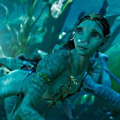 a woman in underwater clothing with her face painted like a mermaid and other people behind her