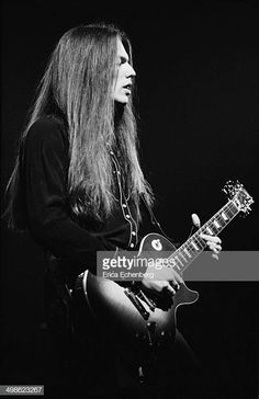 a man with long hair playing an electric guitar