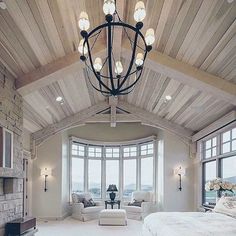 a bedroom with a large bed and lots of windows next to a fire place in the corner