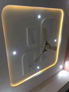 a clock that is on the side of a wall in a room with lights around it