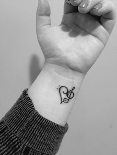 a woman's wrist with a musical note tattoo on her left hand and a treble in the middle