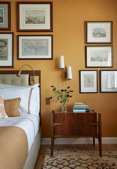 a bedroom with yellow walls and pictures on the wall above it, along with a bed