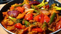 a pan filled with meat and vegetables on top of a wooden table